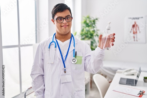 Down syndrome man wearing doctor uniform holding sanitizer gel hands at clinic