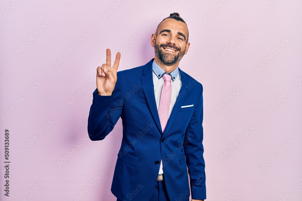 Young hispanic man wearing business suit and tie smiling looking to the camera showing fingers doing victory sign. number two. Young hispanic man wearing business suit and tie smiling looking to the camera showing fingers doing victory sign. number two.