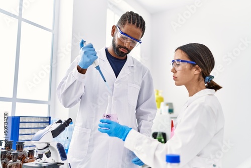 Man and woman scientist partners working using test tube and pipette at laboratory