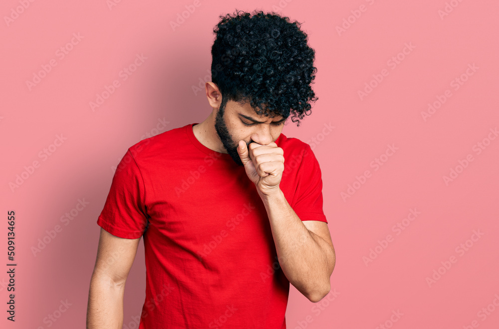 Young arab man with beard wearing casual red t shirt feeling unwell and coughing as symptom for cold or bronchitis. health care concept. Young arab man with beard wearing casual red t shirt feeling unwell and coughing as symptom for cold or bronchitis. health care concept.