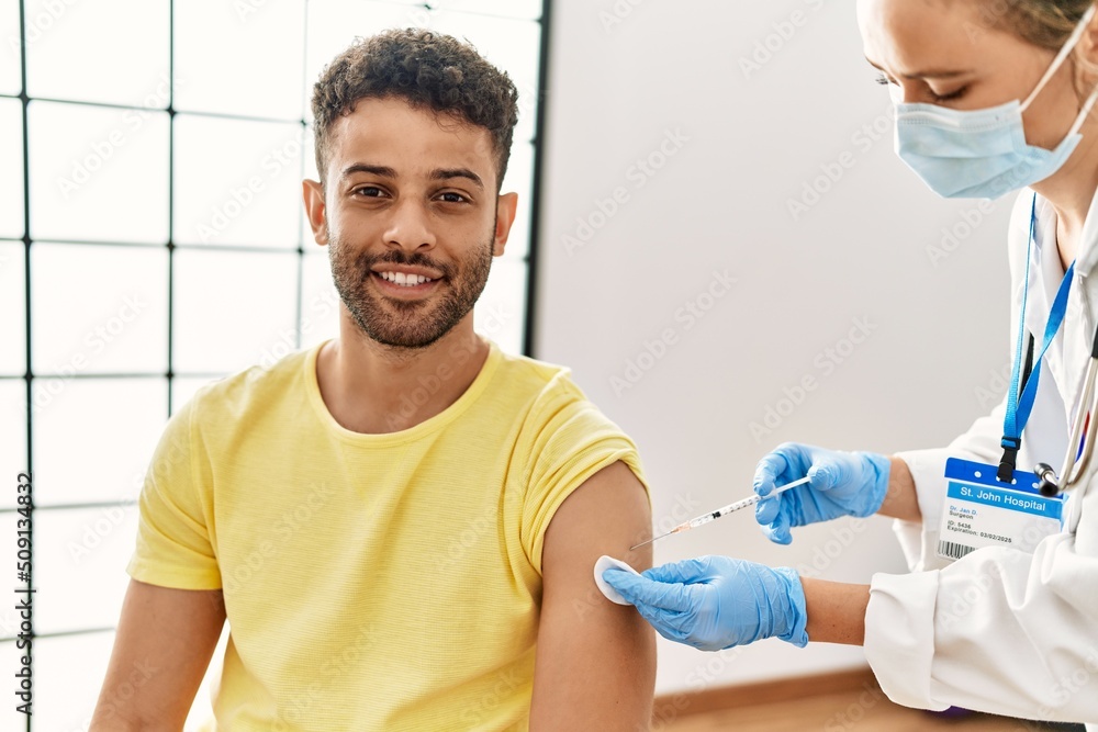 Fototapeta premium Young arab man smiling happy waiting for covid-19 vaccine at hospital.