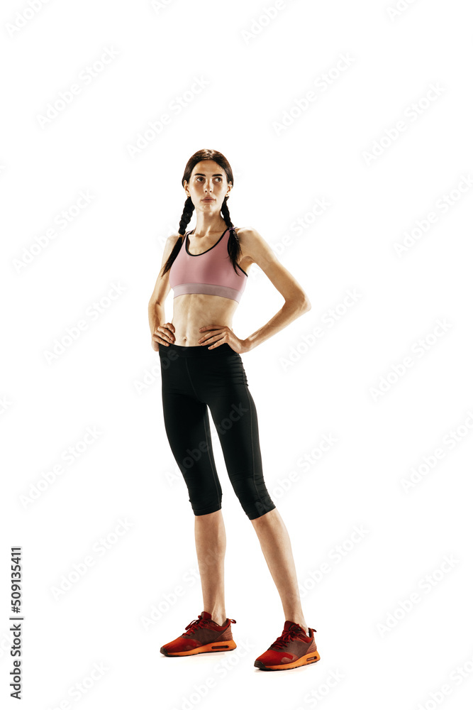 Portrait of young girl, female athlete in sports uniform posing isolated on white studio background. Sport, track-and-field athletics, competition concept Portrait of young girl, female athlete in sports uniform posing isolated on white studio background. Sport, track-and-field athletics, competition concept