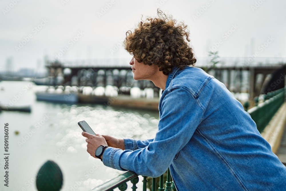 Obraz premium Young hispanic man using smartphone at marina port