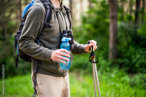 Image of man holding bottle of water and hiking.