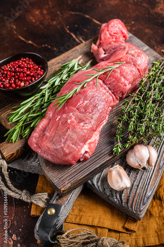 Uncooked beef veal tenderloin, raw meat for fillet mignon steaks. Dark background. Top view