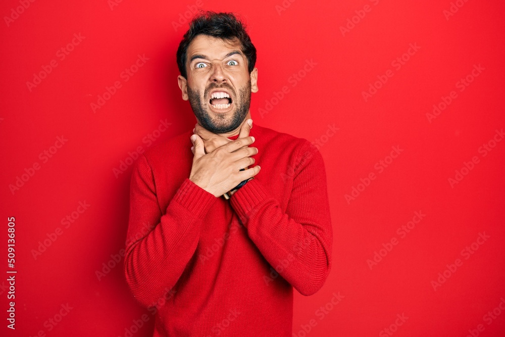 Handsome man with beard wearing casual red sweater shouting suffocate because painful strangle. health problem. asphyxiate and suicide concept.