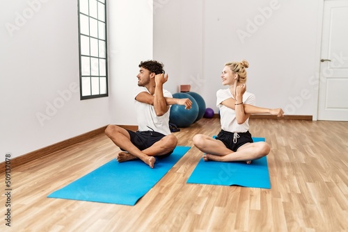 Young sporty couple smiling happy stretching at sport center.