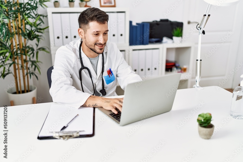 Young hispanic man wearing doctor uniform working at clinic Young hispanic man wearing doctor uniform working at clinic
