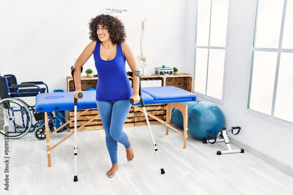 Fototapeta premium Young middle east woman walking using crutches at clinic