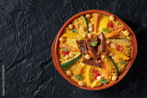 Moroccan couscous with meat, traditional festive dinner, shot from the top on a black background with copy space photo