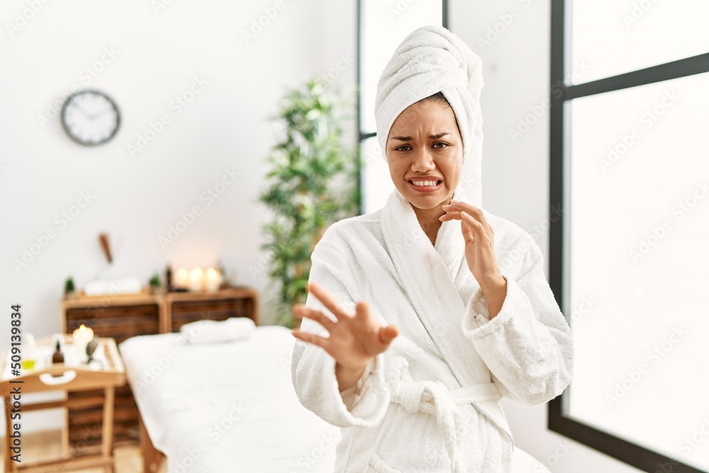 Young brunette woman wearing towel and bathrobe standing at beauty center disgusted expression, displeased and fearful doing disgust face because aversion reaction. with hands raised Young brunette woman wearing towel and bathrobe standing at beauty center disgusted expression, displeased and fearful doing disgust face because aversion reaction. with hands raised