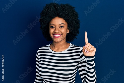 Young african american woman wearing casual clothes showing and pointing up with finger number one while smiling confident and happy.