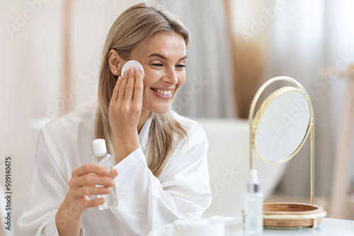 Positive beautiful lady erasing make up, using micellar water photo