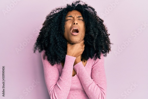 African american woman with afro hair wearing casual pink shirt shouting and suffocate because painful strangle. health problem. asphyxiate and suicide concept.