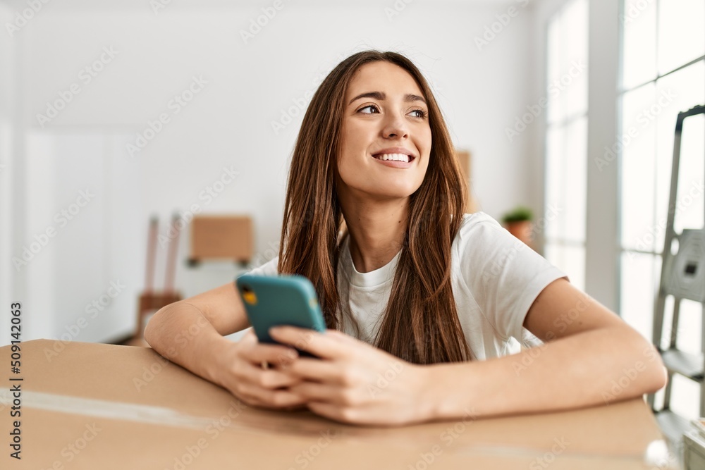 Young hispanic woman smiling confident using smartphone at new home Young hispanic woman smiling confident using smartphone at new home