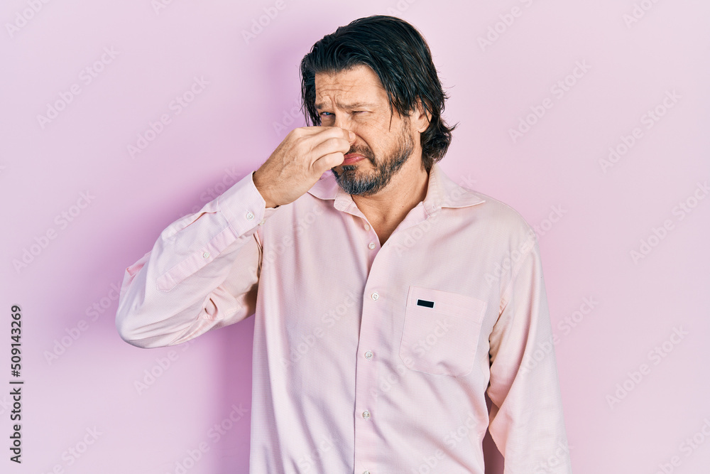 Middle age caucasian man wearing casual clothes smelling something stinky and disgusting, intolerable smell, holding breath with fingers on nose. bad smell Middle age caucasian man wearing casual clothes smelling something stinky and disgusting, intolerable smell, holding breath with fingers on nose. bad smell