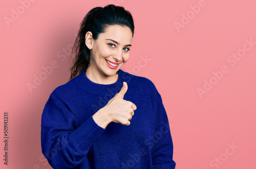 Young hispanic woman wearing casual clothes doing happy thumbs up gesture with hand. approving expression looking at the camera showing success.