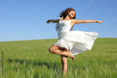 фотографія Happy woman twirling with white dress in a field