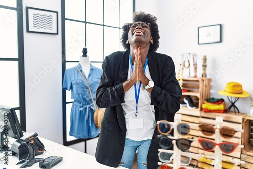 Stampa su tela African young woman working as manager at retail boutique begging and praying with hands together with hope expression on face very emotional and worried