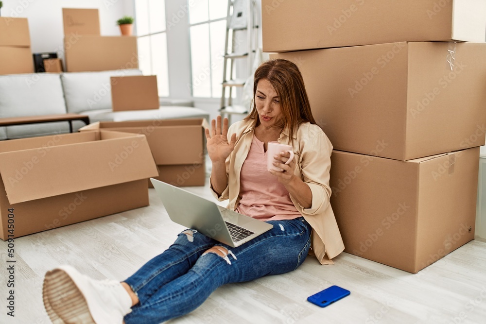 Middle age caucasian woman having video call using laptop sitting on the floor at new home. Middle age caucasian woman having video call using laptop sitting on the floor at new home.