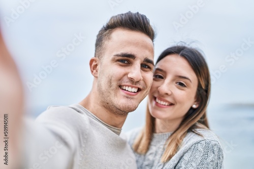 Man and woman couple hugging each other make selfie by camera at seaside