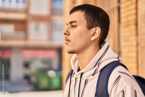 Young man student standing with relaxed expression at street