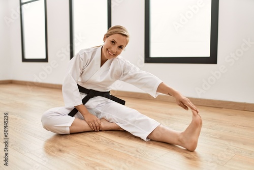 Young caucasian woman wearing karate uniform stretching at sport center © Krakenimages.com