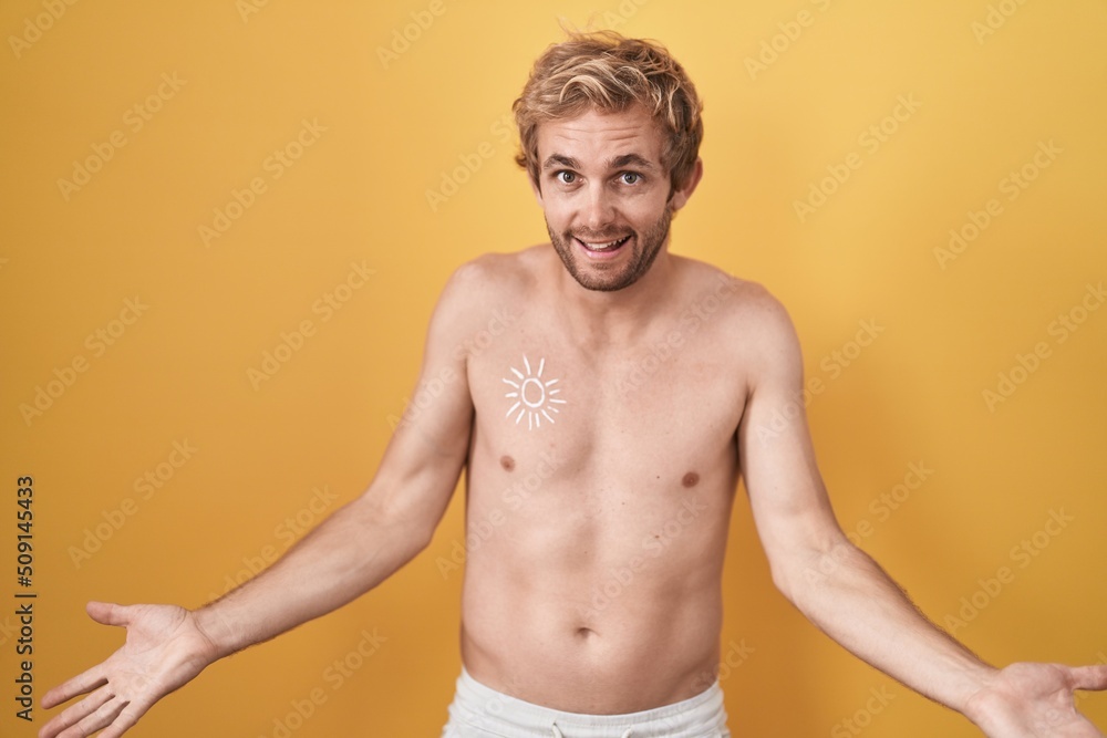 Caucasian man standing shirtless wearing sun screen smiling cheerful with open arms as friendly welcome, positive and confident greetings