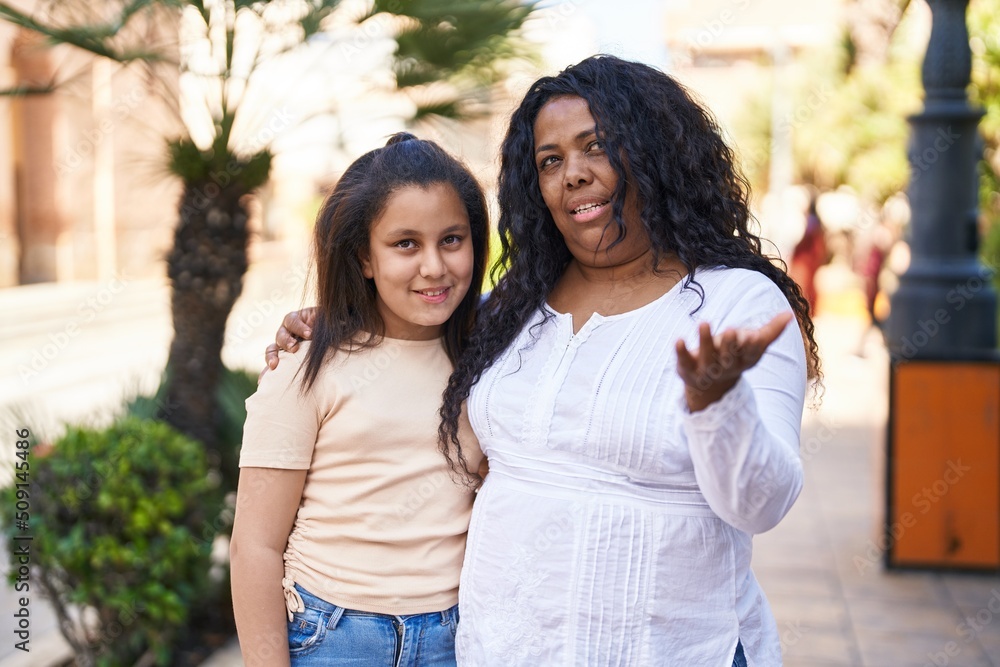 Mother and daughter standing together speaking at park Mother and daughter standing together speaking at park