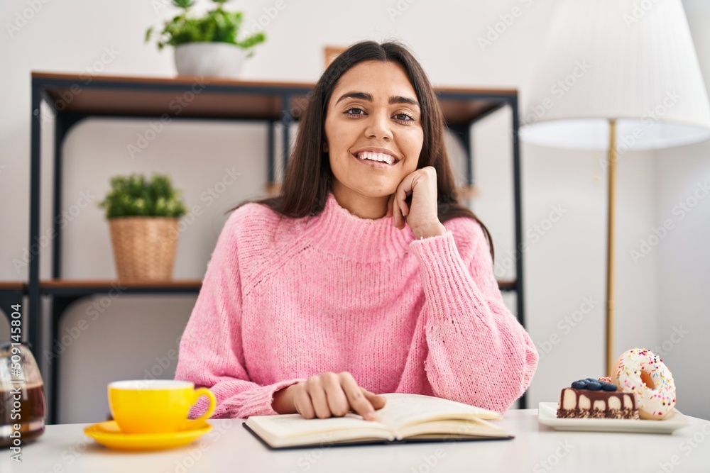 Young hispanic woman reading book having breakfast at home Young hispanic woman reading book having breakfast at home