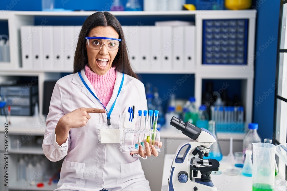 Young brunette woman working at scientist laboratory smiling happy pointing with hand and finger Young brunette woman working at scientist laboratory smiling happy pointing with hand and finger