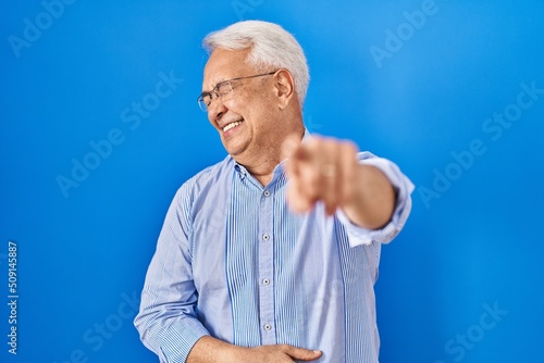 Hispanic senior man wearing glasses laughing at you, pointing finger to the camera with hand over body, shame expression © Krakenimages.com
