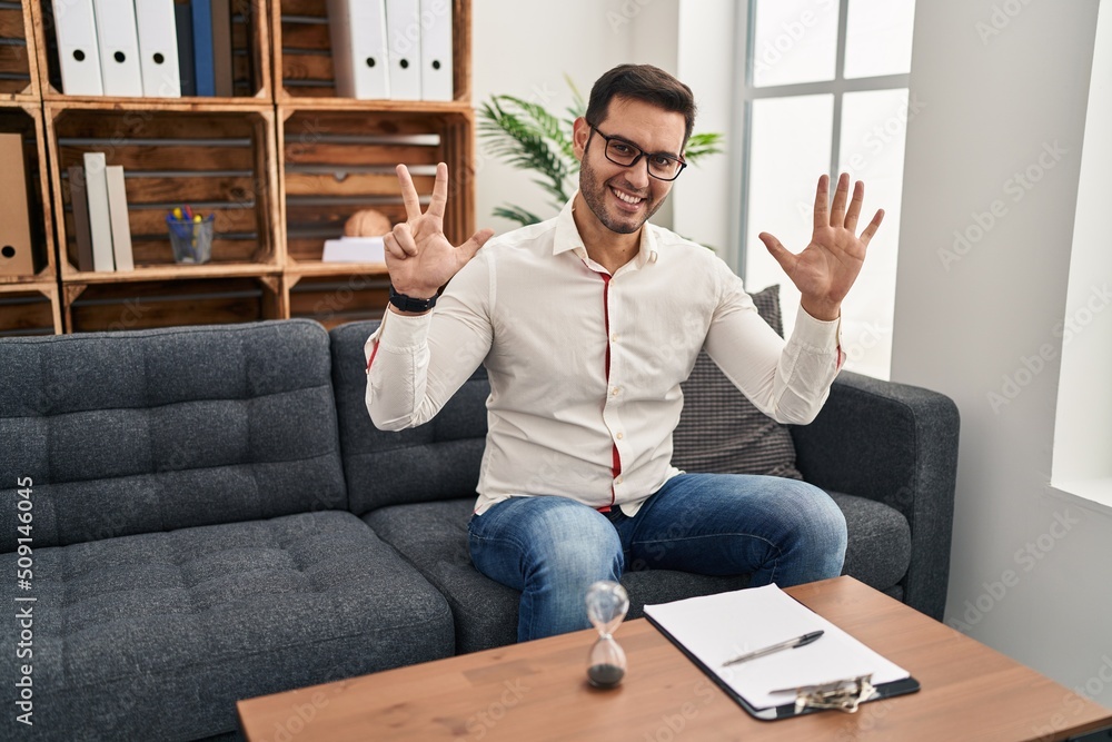 Young hispanic man with beard working at consultation office showing and pointing up with fingers number eight while smiling confident and happy. Young hispanic man with beard working at consultation office showing and pointing up with fingers number eight while smiling confident and happy.