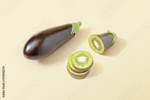 Surreal composition with sliced fresh eggplant and kiwi on pastel sandy background. Minimal vegan concept.
