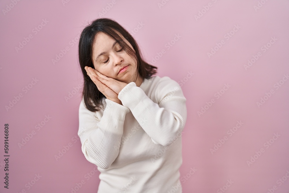 Woman with down syndrome standing over pink background sleeping tired dreaming and posing with hands together while smiling with closed eyes. Woman with down syndrome standing over pink background sleeping tired dreaming and posing with hands together while smiling with closed eyes.