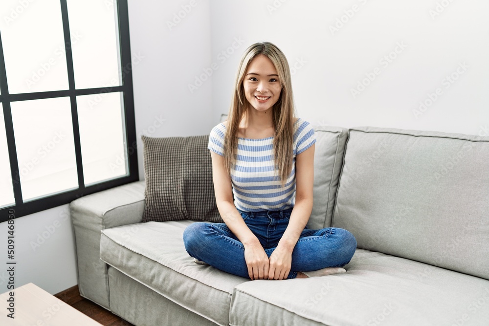 Asian young woman sitting on the sofa at home with a happy and cool smile on face. lucky person. Asian young woman sitting on the sofa at home with a happy and cool smile on face. lucky person.