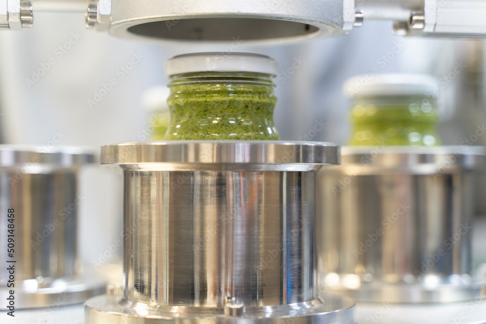 close up on Pesto sauce Industrial process. vacuum sealing machine for canned food. production of Pesto sauce. Vacuum Seamer for Cylindrical Cans of Rotary Type. close up on Pesto sauce Industrial process. vacuum sealing machine for canned food. production of Pesto sauce. Vacuum Seamer for Cylindrical Cans of Rotary Type.