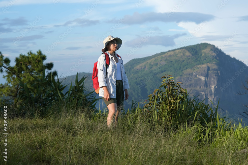 Happy female hiker with a backpack stands on top of a mountain enjoying nature and looking at the sky. Freedom and happiness, achievement in mountains. Happy female hiker with a backpack stands on top of a mountain enjoying nature and looking at the sky. Freedom and happiness, achievement in mountains.