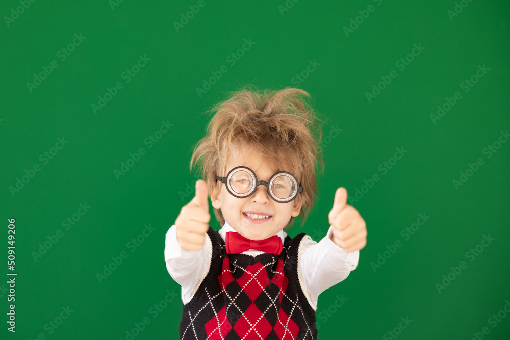 Happy child in class against green chalkboard Happy child in class against green chalkboard