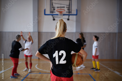 A rear view of young woman basketball player in gym during match.