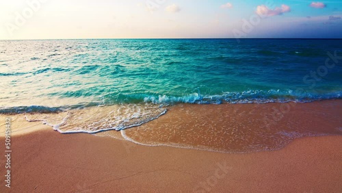 Tropical sea at sunset. Maldivian beach with gentle rolling waves on the tropical island of Thulusdhoo in Maldives