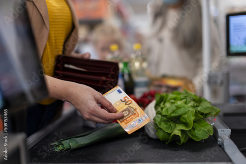 Close-up of woman giving money at the cash desk in supermarket