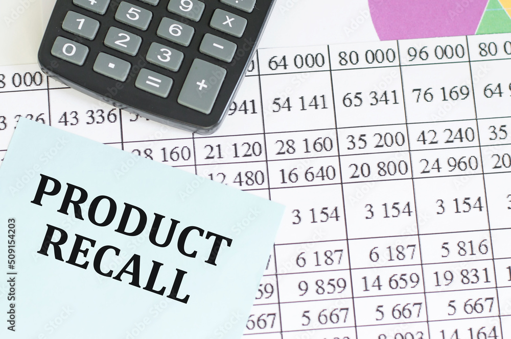a card with text Product Recall on the background of financial reports next to calculator and chart a card with text Product Recall on the background of financial reports next to calculator and chart