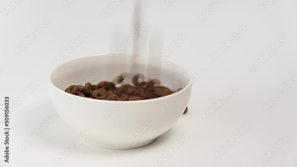 Flaks on white background. Chocolate rings filling into white container. Nutritious breakfast. Healthy breakfast. Marketing, advertising and branding use. Child breakfast time. Free space for text. Flaks on white background. Chocolate rings filling into white container. Nutritious breakfast. Healthy breakfast. Marketing, advertising and branding use. Child breakfast time. Free space for text.