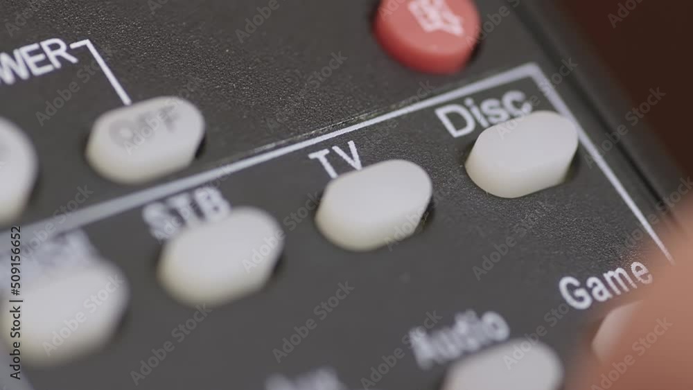 Super macro of a Caucasian male hand pushing backlit button on remote control. Super macro of a Caucasian male hand pushing backlit button on remote control.