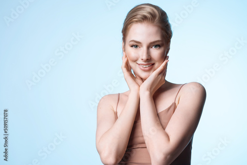 Young blond woman smiling and touching skin. Girl with natural beauty. Cosmetology and dermatology procedure advertising