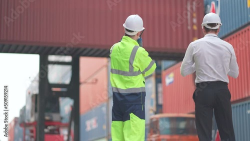 Caucasian cargo container worker and manager discuss together and plan about tranportation in front of working crane carry container tank. photo
