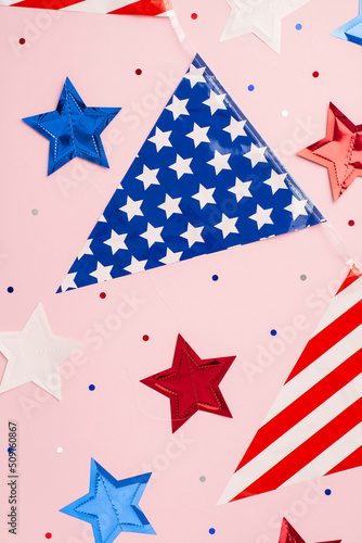 USA Independence Day concept. Top view vertical photo of national flag garland stars and confetti on isolated pastel pink background