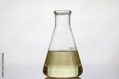 yellow oil on scientific glassware on white background. example lubricant oil for testing.