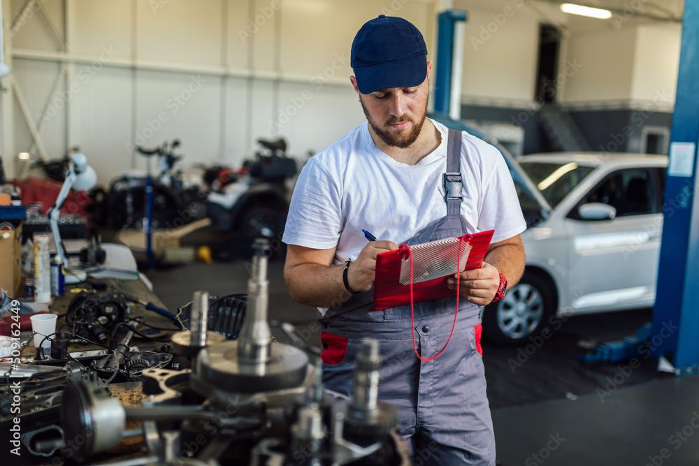 Man writing on a clipboard in a garage. Man writing on a clipboard in a garage.